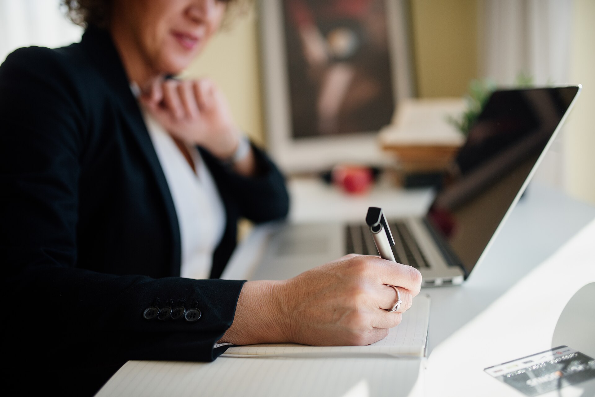 A planner taking notes during a consultation at a desk with a laptop.