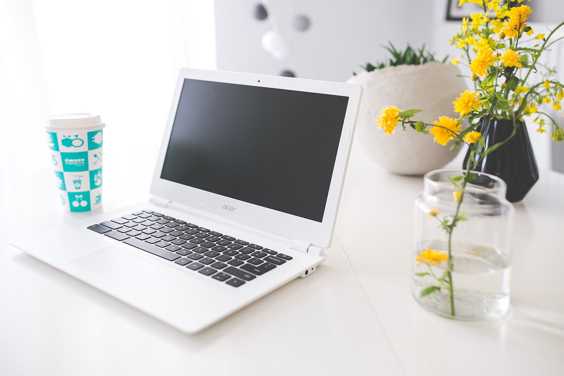 A tidy freelance workspace: laptop, notebook and a cup of coffee on a wooden desk.